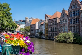 brown and white concrete building beside river under blue sky during daytime