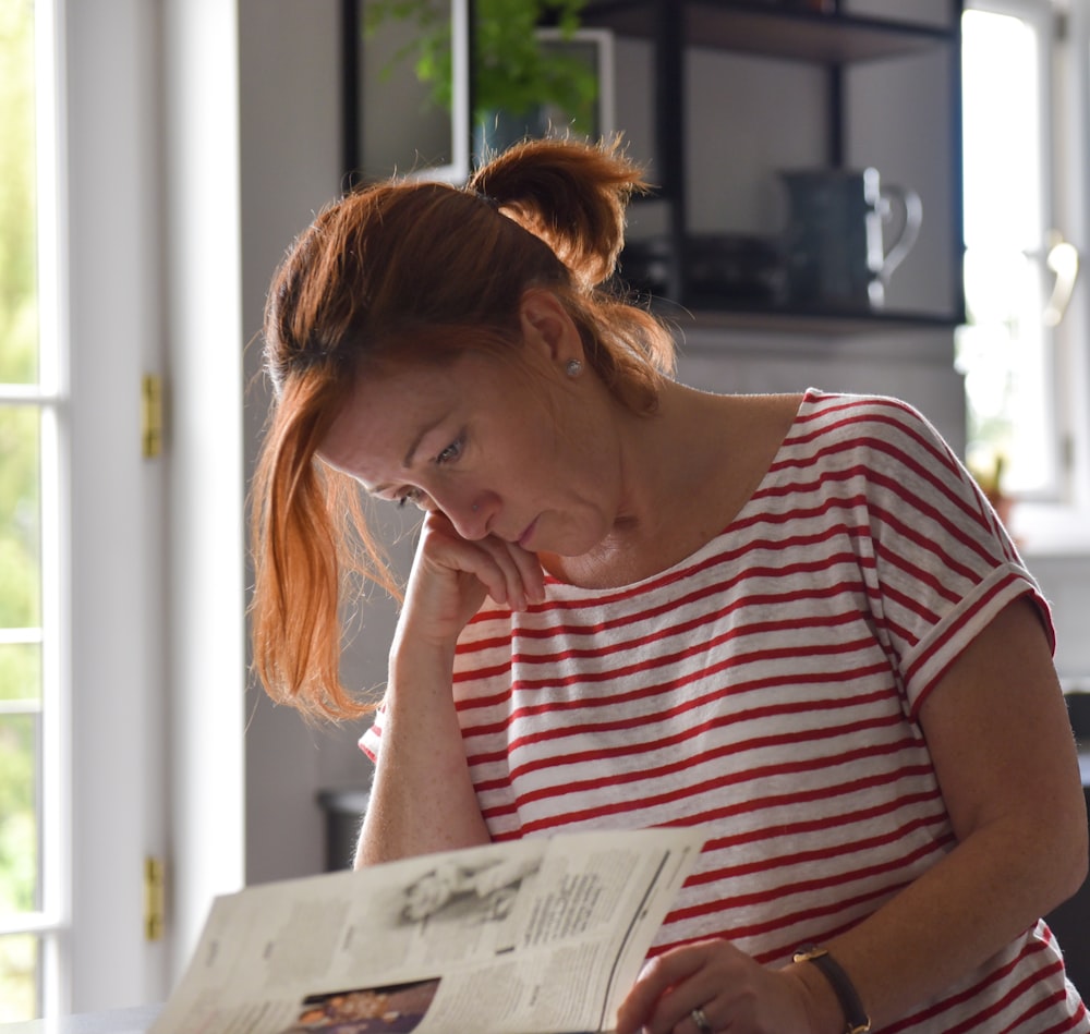 woman in white and black striped shirt reading book