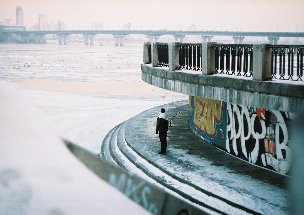 man in black jacket and black pants walking on snow covered ground during daytime