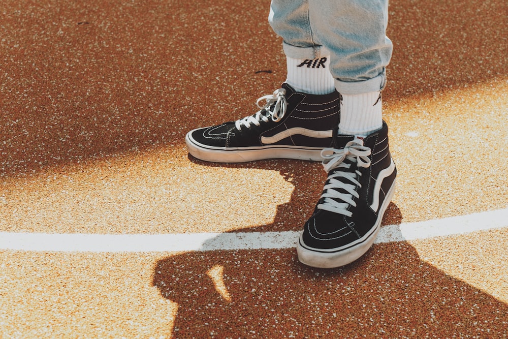 person in blue denim jeans and black and white adidas sneakers