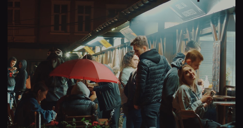 people standing near red umbrella during daytime