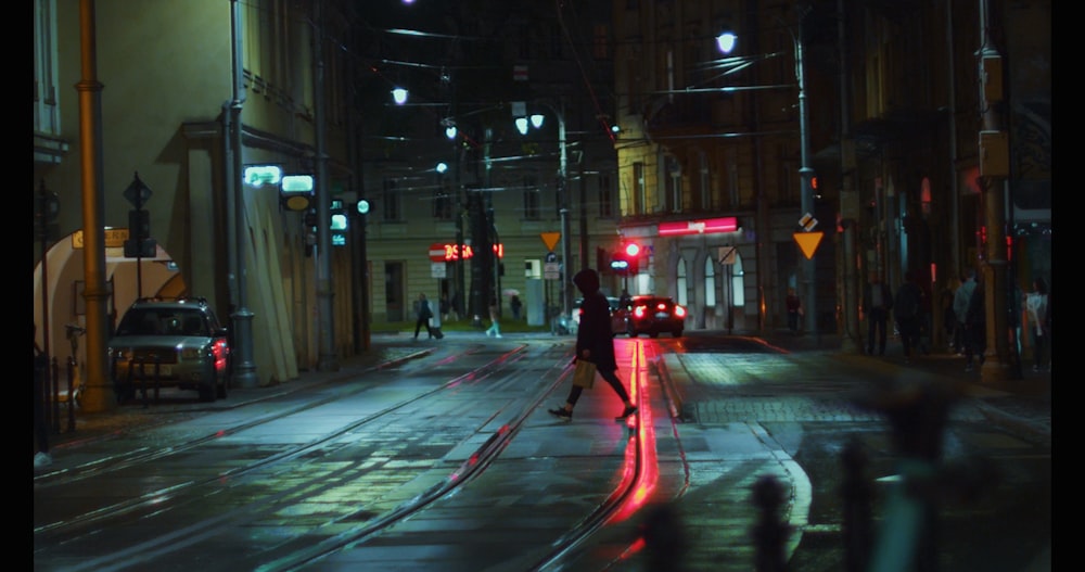 person in black jacket walking on sidewalk during night time