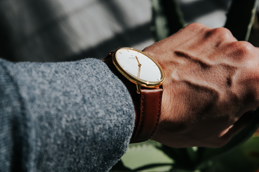 person wearing brown leather strap gold round analog watch