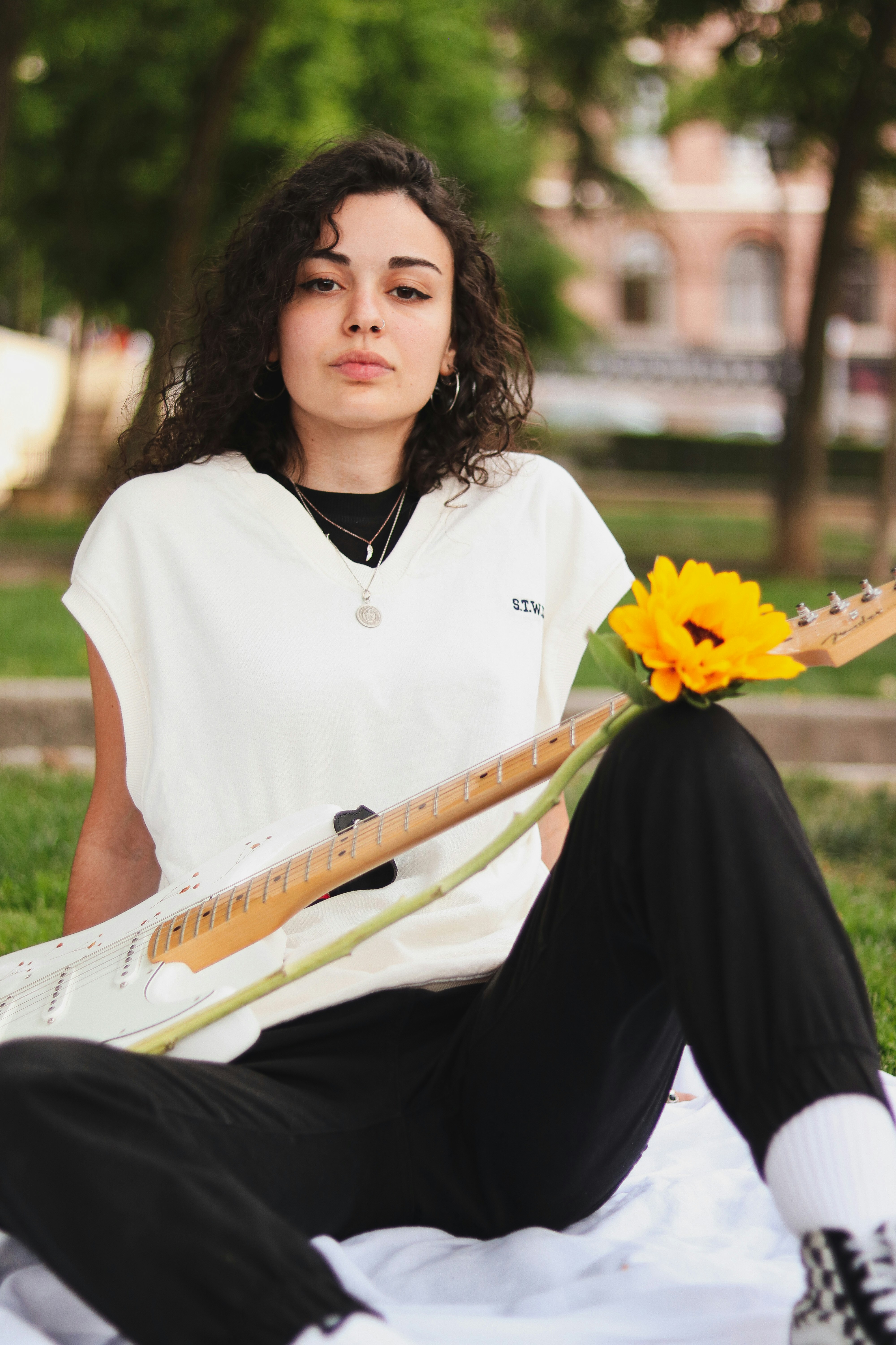 woman in white shirt and black pants holding yellow flower