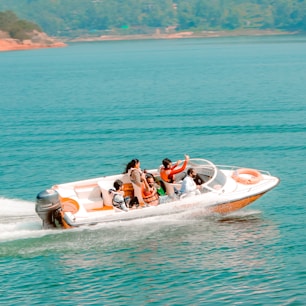 2 people riding on white and red inflatable boat on blue sea during daytime