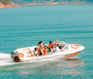 2 people riding on white and red inflatable boat on blue sea during daytime