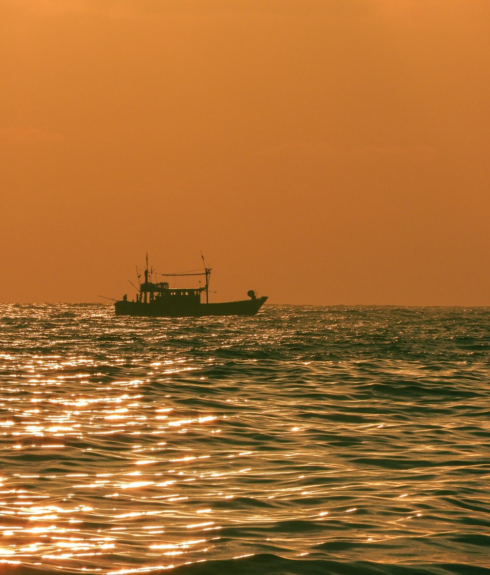 silhouette of boat on sea during sunset