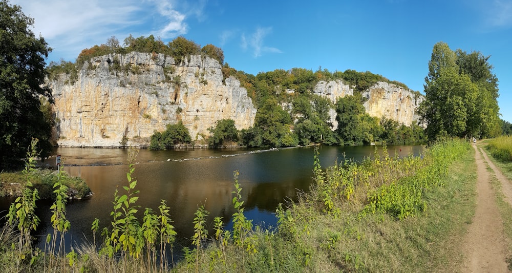 Braune Felsformation neben Gewässer unter blauem Himmel tagsüber