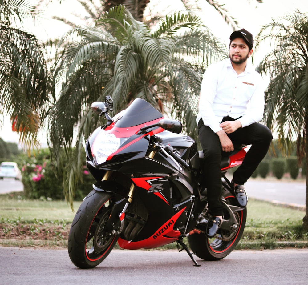 man in white dress shirt and black pants riding black sports bike