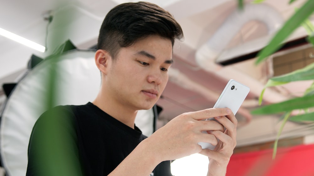 Hombre en camiseta negra de cuello redondo con iPhone 6 plateado
