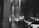 A dimly lit interior of a place of worship with religious icons on the walls. Lit candles are placed on a stand, casting a gentle glow. Wooden pews are positioned to the right, and the atmosphere is serene and contemplative.