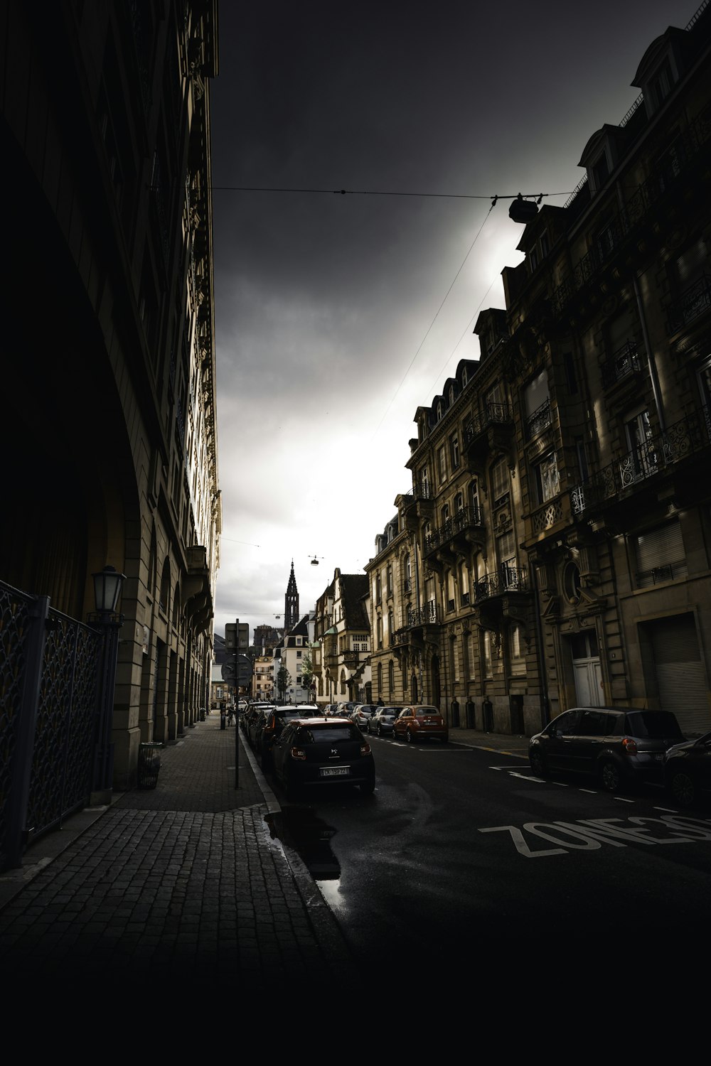 cars parked on side of the road in between buildings