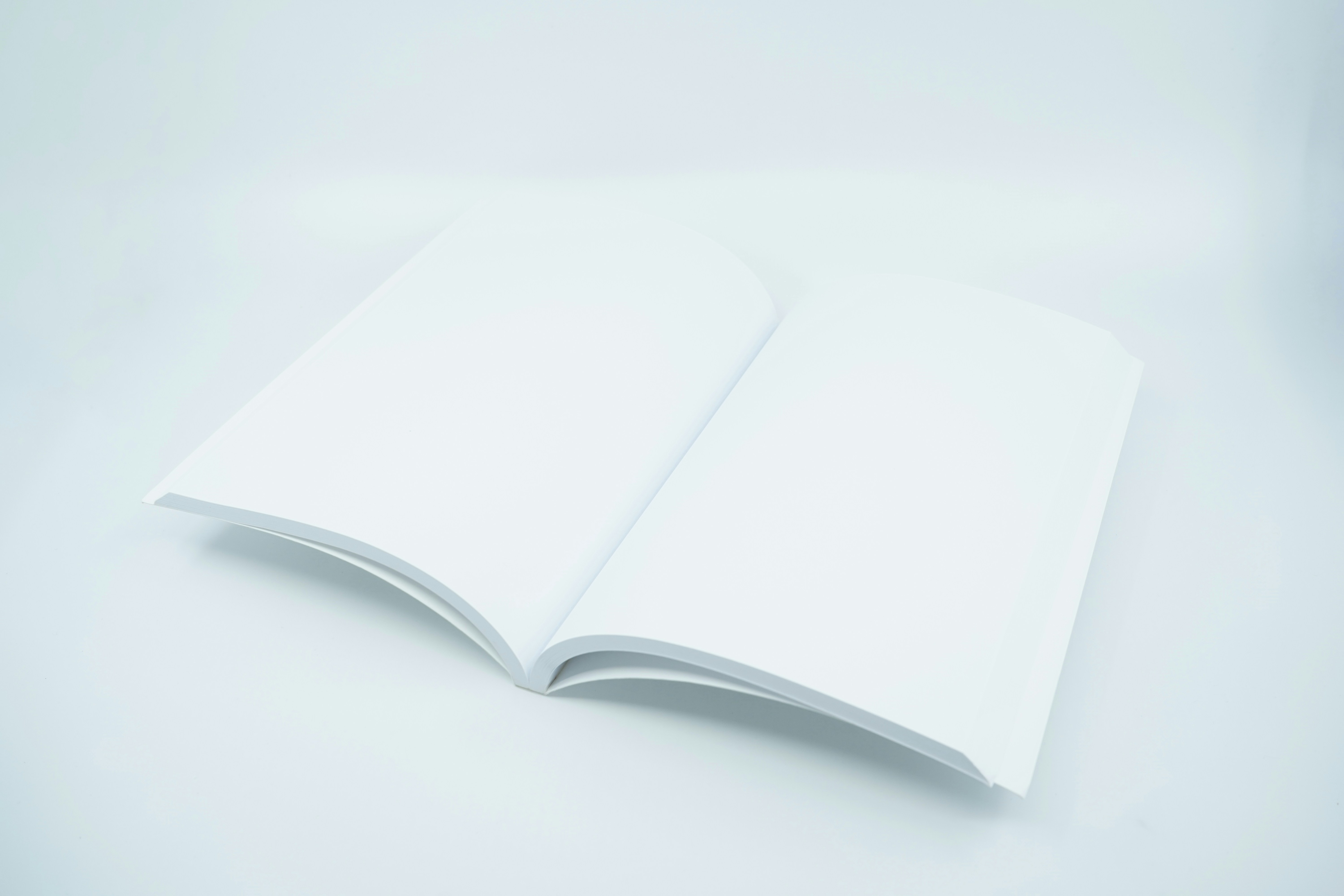 Minimal style photo featuring a blank white softcover book or magazine mockup on a gray studio background scene.