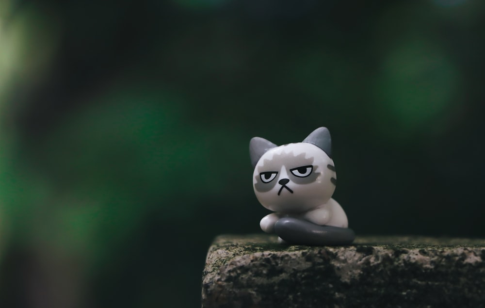 Figurina bianca del gatto sulla roccia marrone