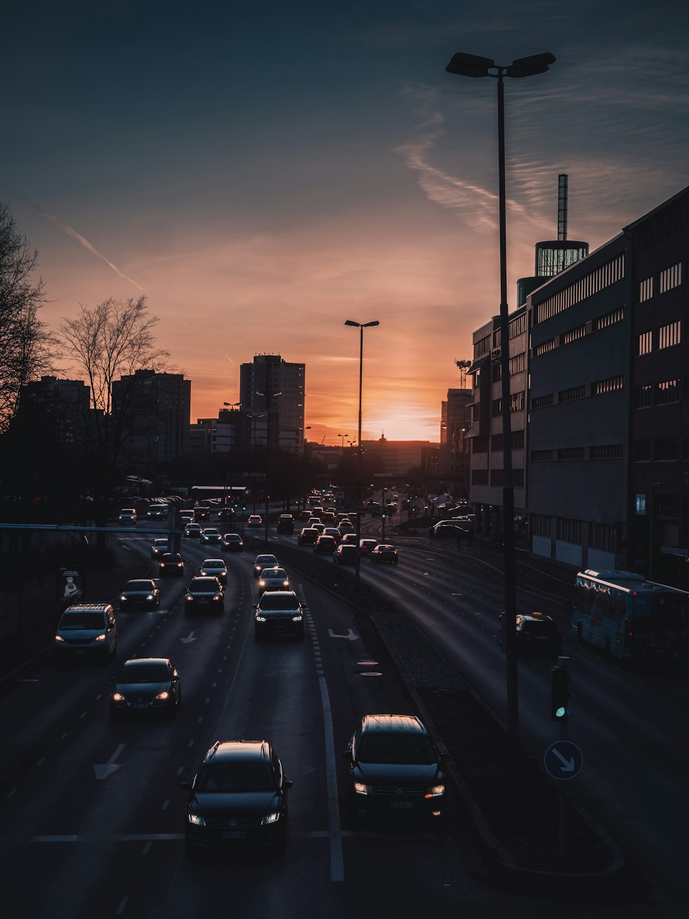 Autos auf der Straße in der Nähe von Gebäuden während des Sonnenuntergangs