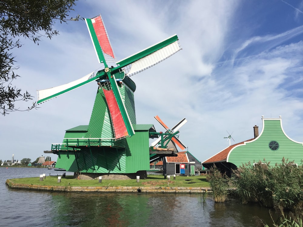 green windmill near body of water during daytime