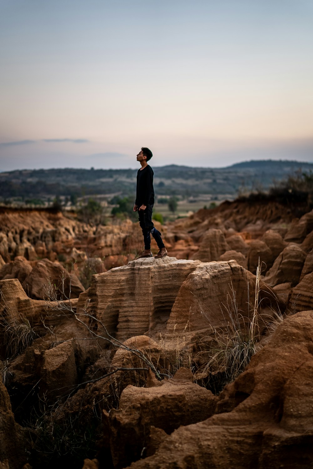 man in black jacket standing on brown rock formation during daytime