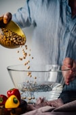 person holding clear glass bowl with corn