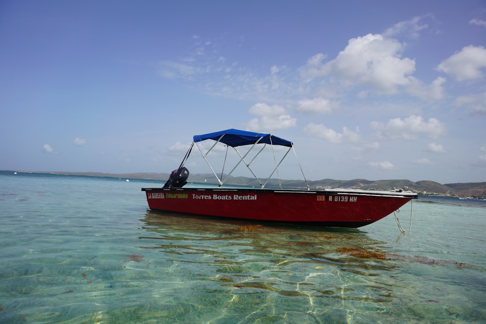 red and blue boat on sea under blue sky during daytime