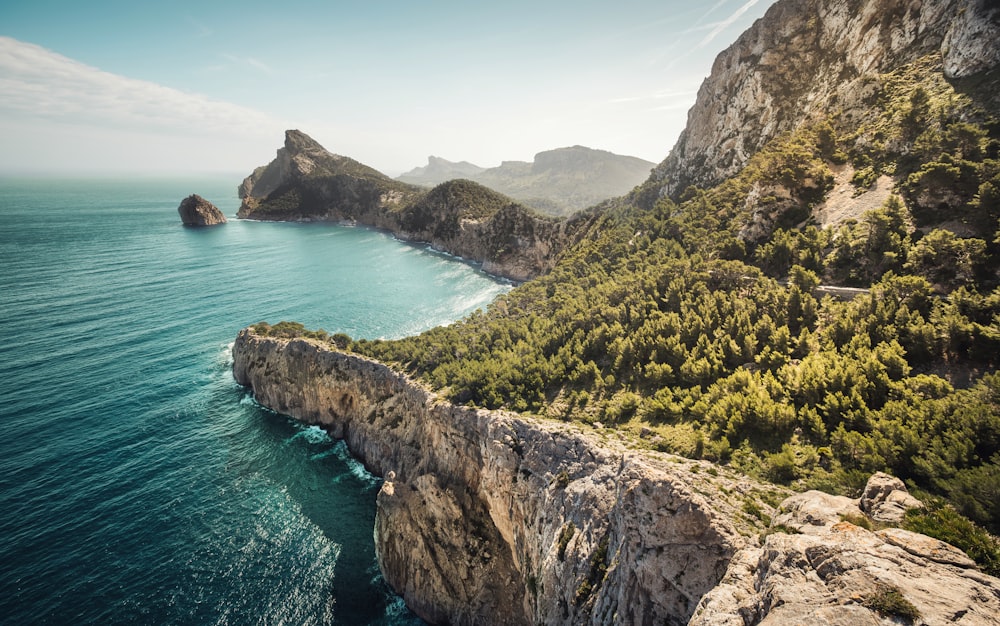 green and brown mountain beside blue sea under blue sky during daytime