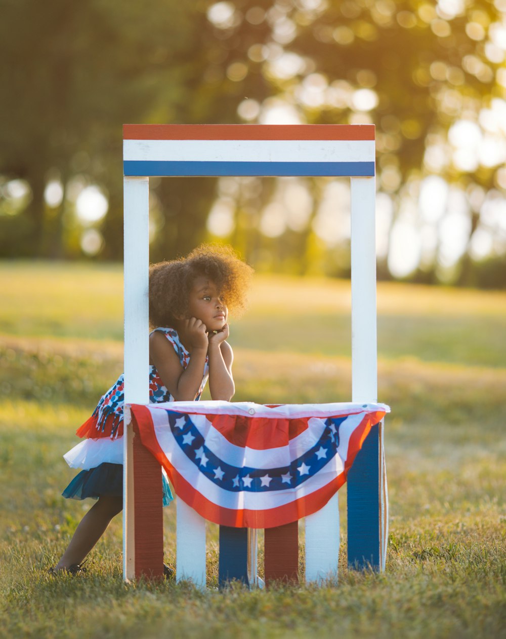 girl in blue and white dress sitting on white and blue wooden chair during daytime