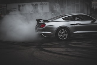 A powerful car mid-burnout, tires smoking and green light reflections highlighting the aggressive stance.