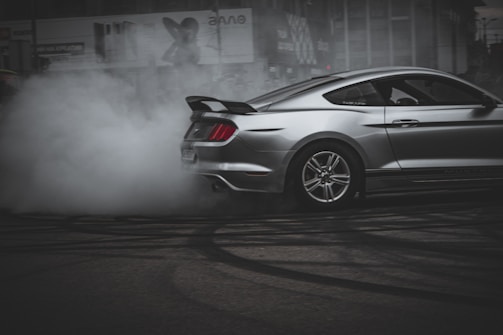 A powerful car mid-burnout, tires smoking and green light reflections highlighting the aggressive stance.