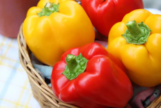 red and yellow bell peppers in brown woven basket