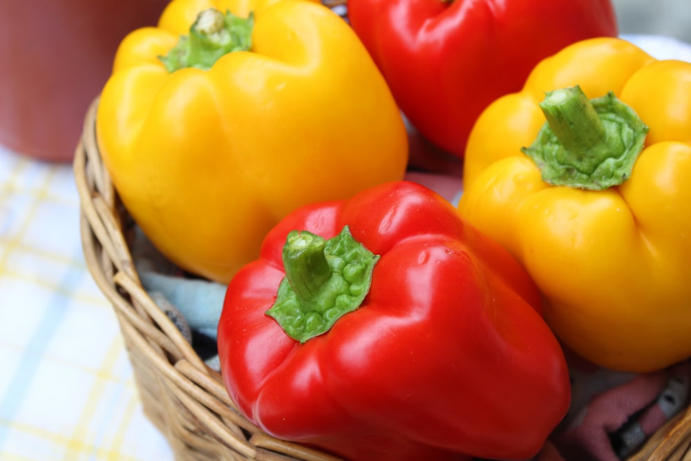 pimientos rojos y amarillos en canasta tejida marrón