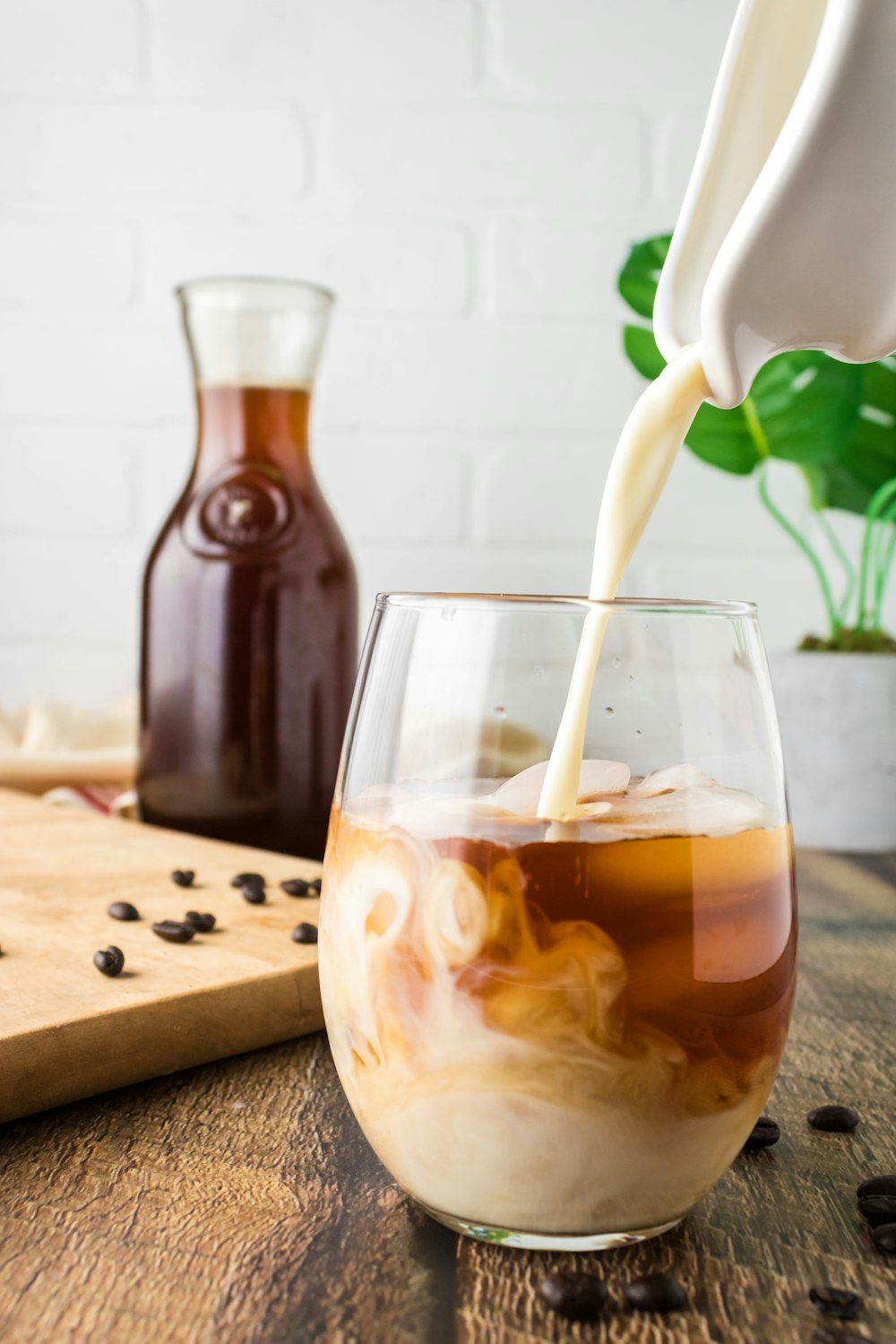 clear drinking glass with brown liquid on brown wooden chopping board