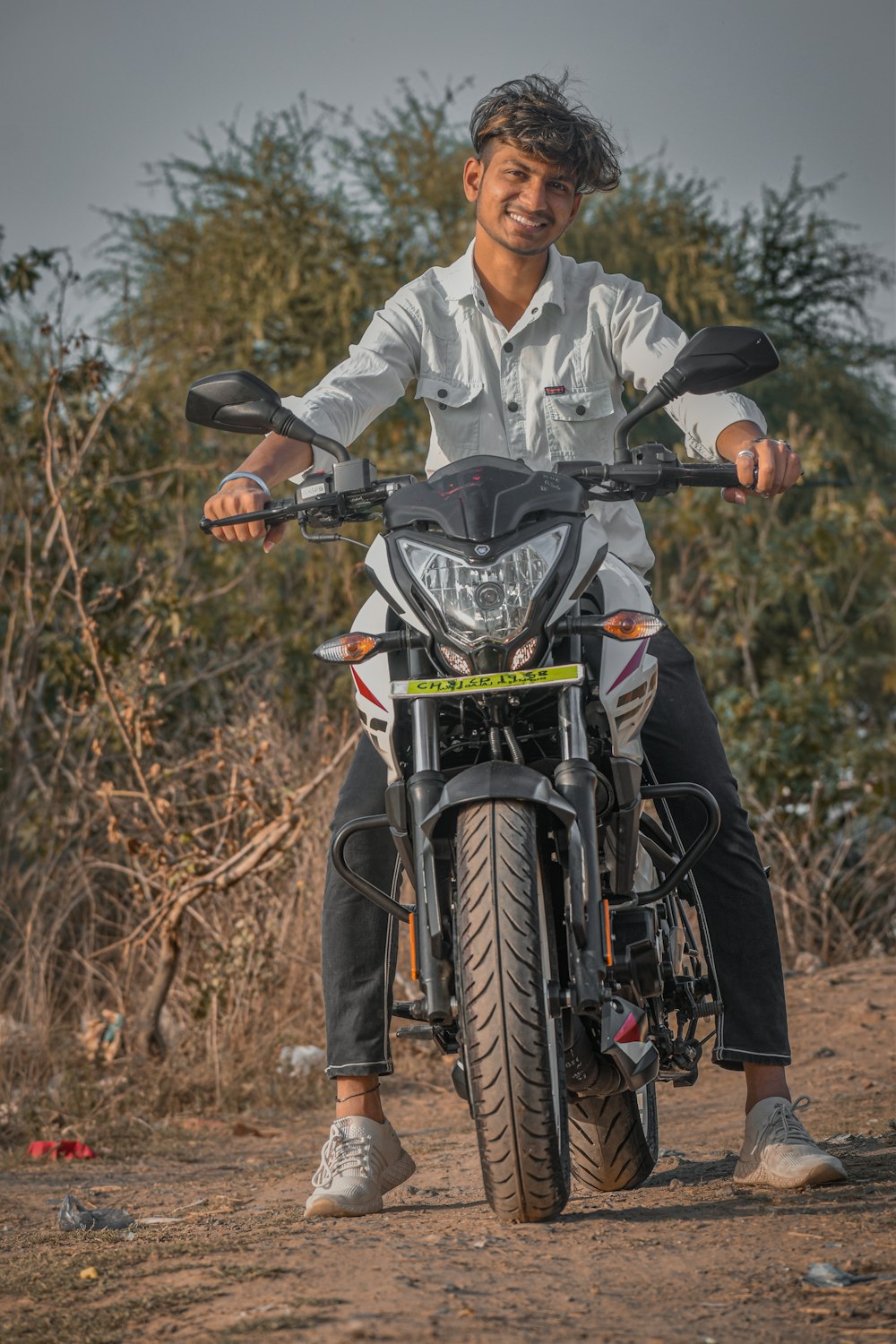 man in gray dress shirt riding on black and blue motorcycle