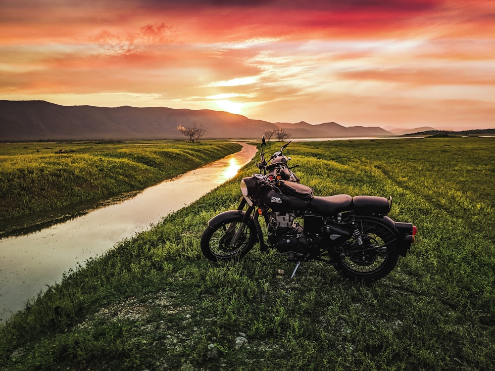 moto noire sur le champ d’herbe verte au coucher du soleil