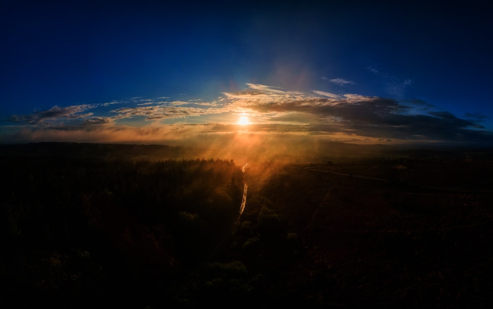 the sun shining through the clouds over a forest