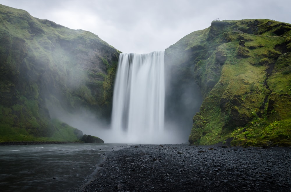 Cascate sulla montagna coperta di erba verde durante il giorno