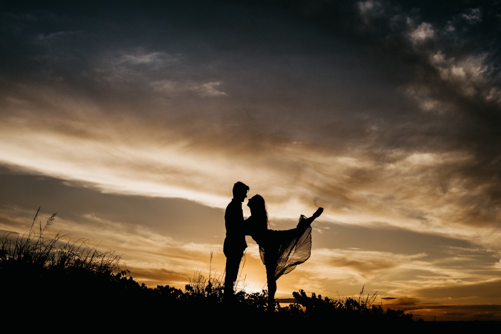 silhouette of man standing on grass field during sunset