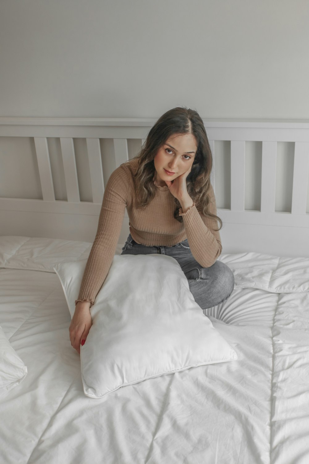 woman in brown long sleeve shirt and blue denim jeans sitting on bed