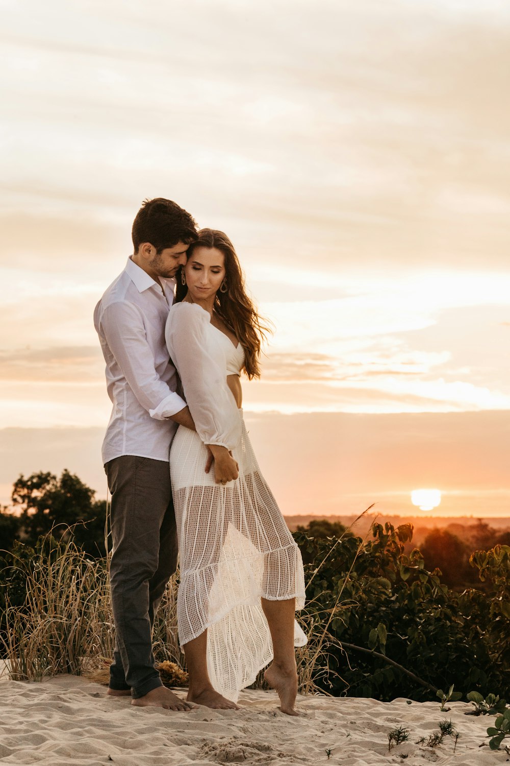 man in white dress shirt hugging woman in white long sleeve dress