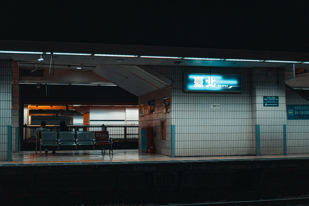 夜間的台鐵月台，牆上亮著「臺北 TAIPEI」站名燈箱
