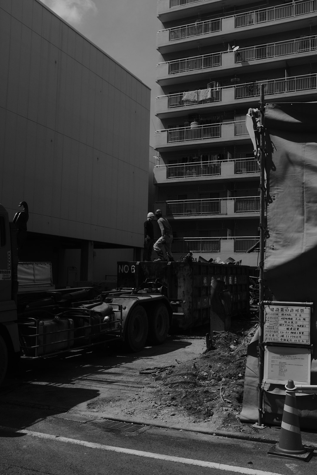 grayscale photo of man in black jacket standing near truck