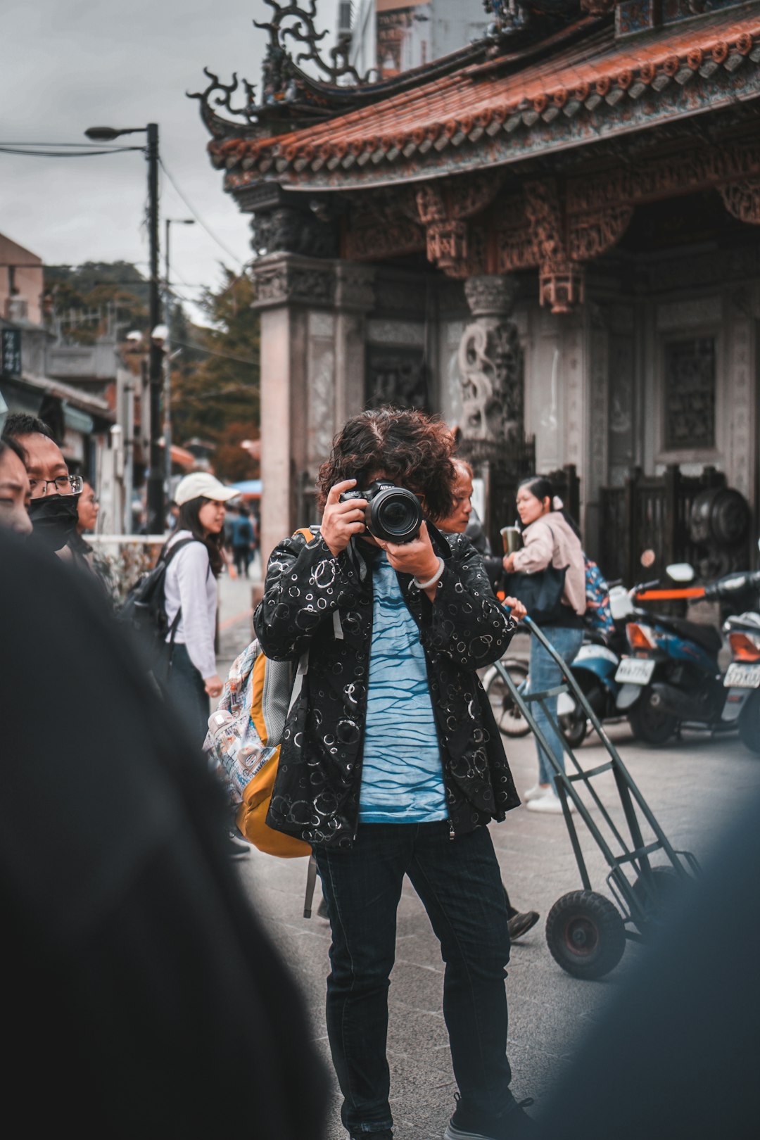 man in black jacket taking photo of people walking on street during daytime