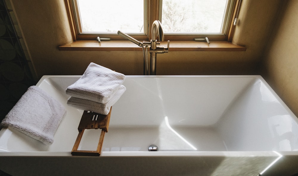 white towel on white ceramic bathtub