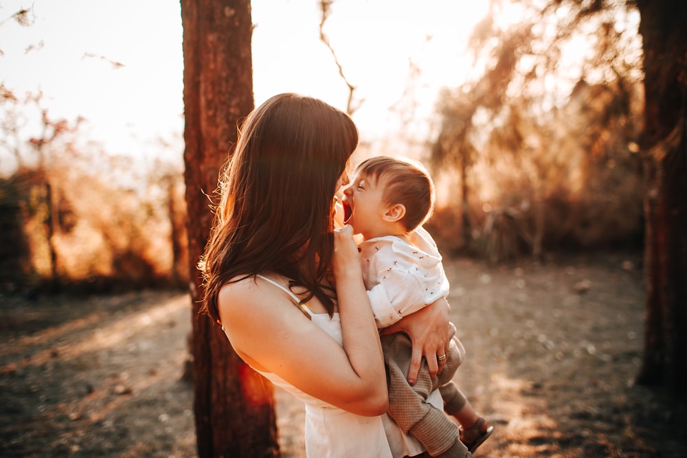 woman in white tank top carrying baby in white dress