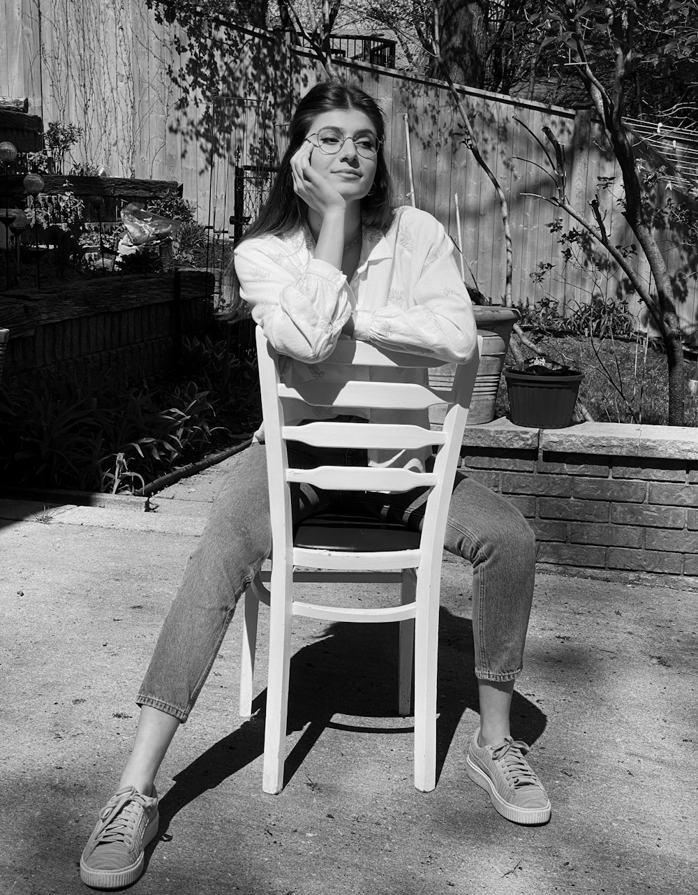 白い木製の椅子に座る白い長袖シャツを着た女性