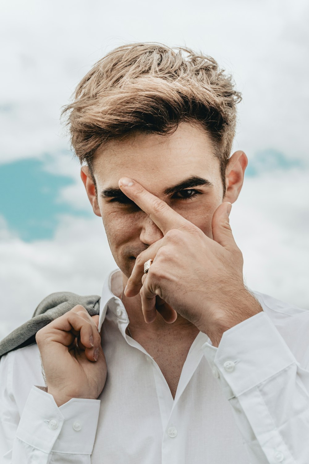 man in white dress shirt covering his face with gray textile