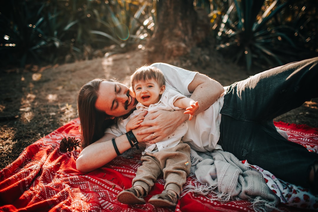 woman in red dress carrying baby in white onesie