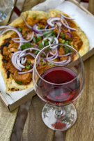 A rustic wooden table set with a variety of pizzas and a glass of red wine.