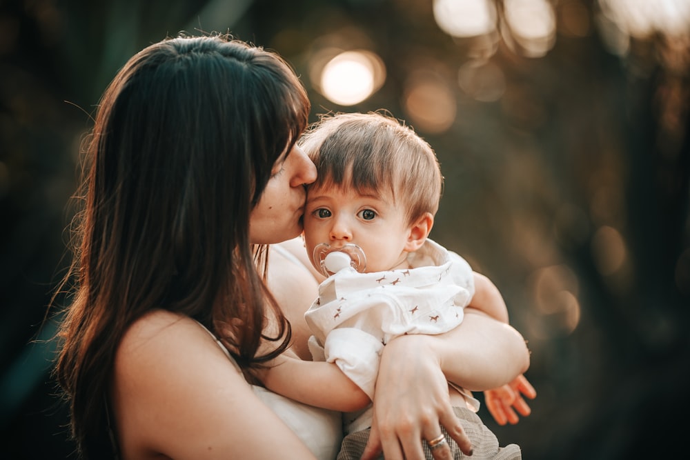 woman in black tank top carrying baby in white tank top