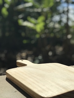 A set of rustic wooden cutting boards arranged on a light kitchen countertop with sunlight streaming through a window