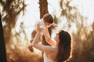 woman in white tank top carrying baby in white dress during daytime