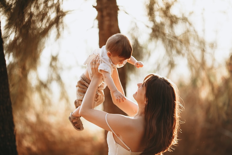 woman in white tank top carrying baby in white dress during daytime